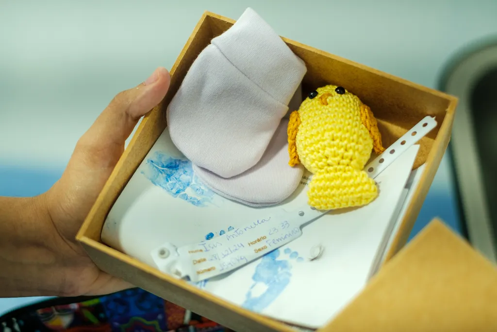 Imagem mostra caixa com sapatinho e pulseirinha de bebê
